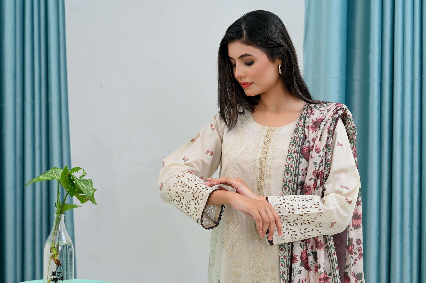 Woman modeling a 3-piece skin embroidered lawn suit with floral details and elegant silhouette in a stylish indoor setting.